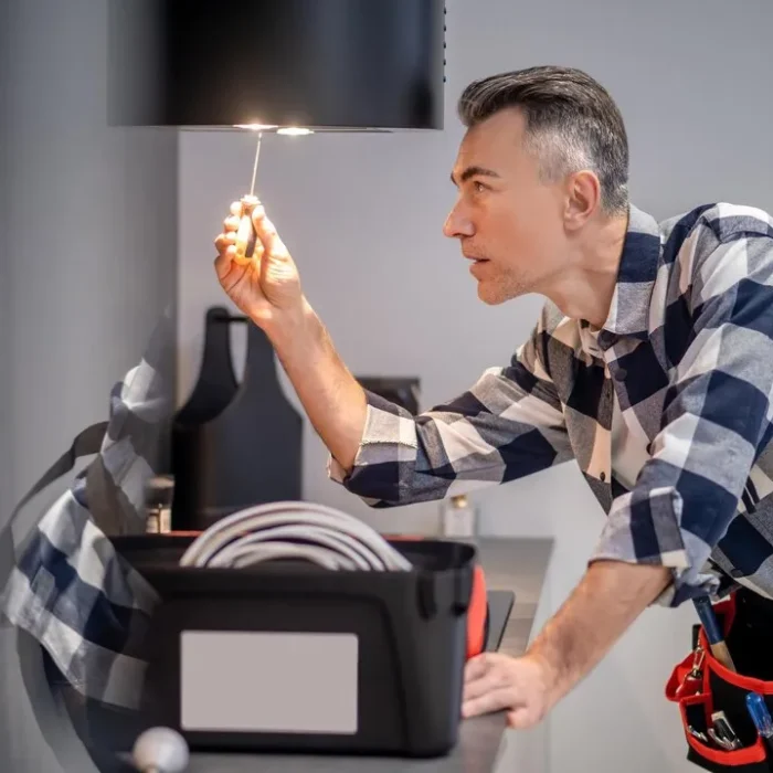 renovation-profile-concentrated-man-touching-screwdriver-lamp-kitchen-range-hood